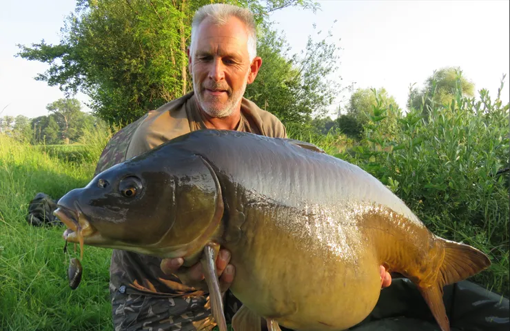 Angler hält einen großen Fisch in den Händen.